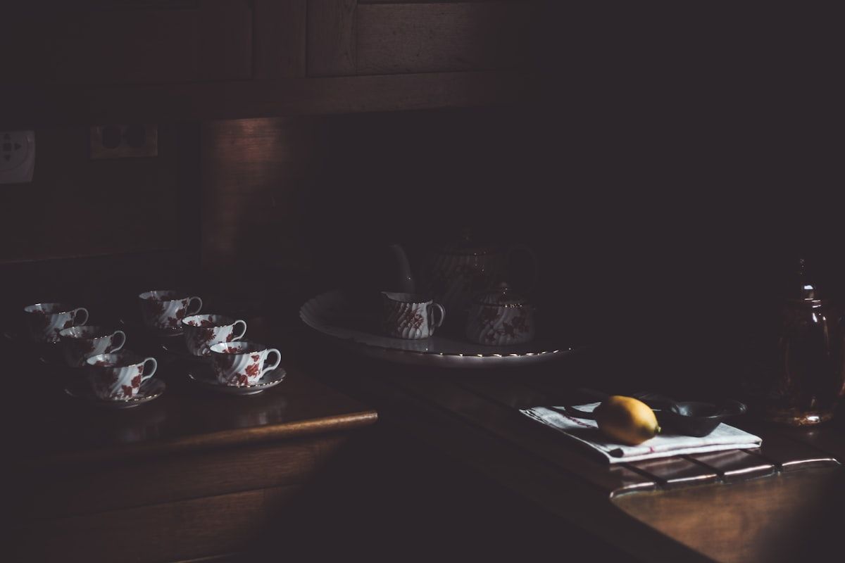 A Chicago apartment kitchen at night with a technician inspecting under the sink and behind the stove using a flashlight, while gel bait tubes, a small dust applicator, and a clipboard sit on the counter next to a few sticky roach traps.