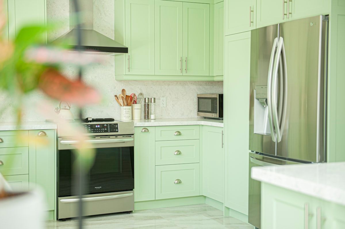 A clean kitchen under-sink cabinet with sealed pipe gaps, dry sinks and counters, a glue trap placed behind the refrigerator, and a person checking a trap near the stove while keeping food in sealed containers